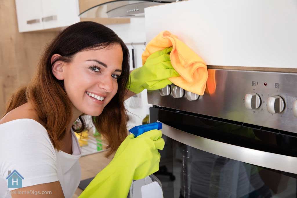 a young girl cleaning oven with the best oven cleaner spray for Baked-on Grease