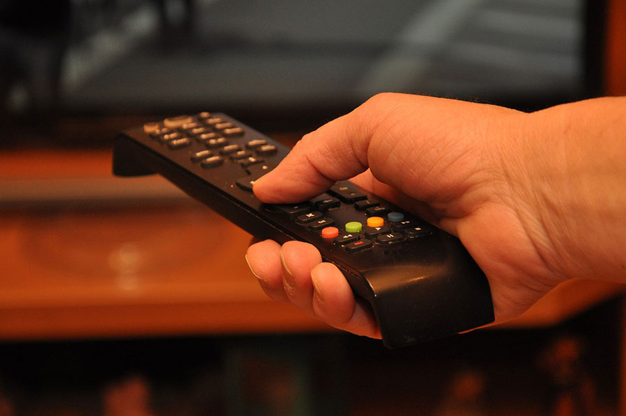 a Remote-control in hand of a man watching TV